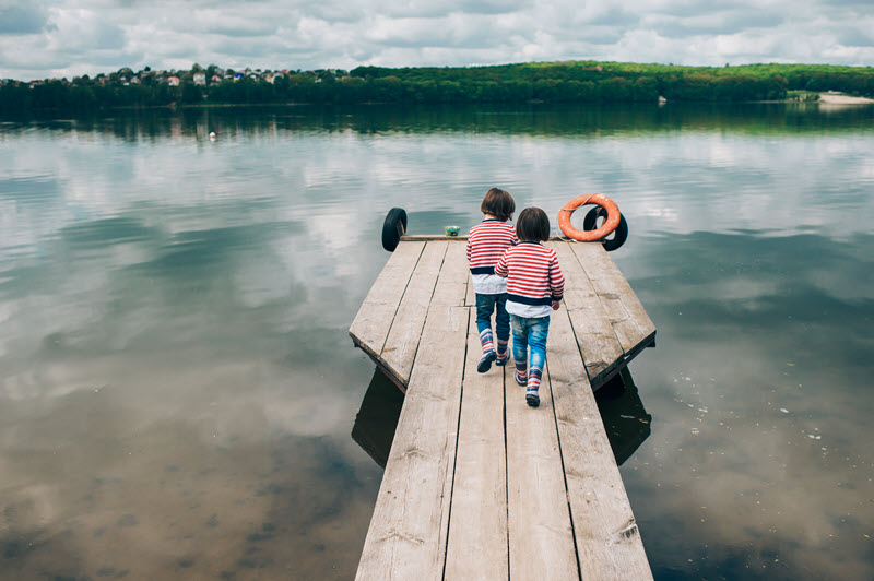 two children on a pier wearing matching red striped long-sleeve shirts