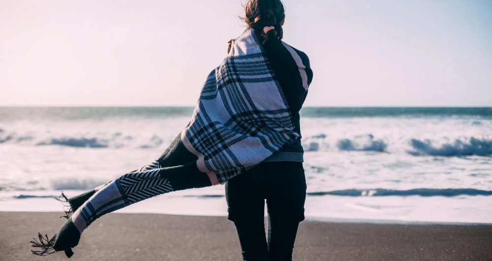 Woman in long scarf looking out to sea